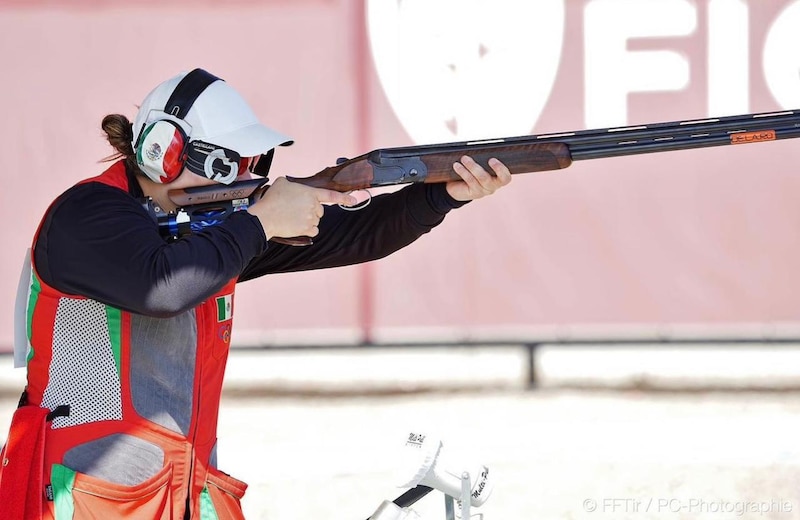 Mujer mexicana dispara una escopeta en una competencia de tiro deportivo.