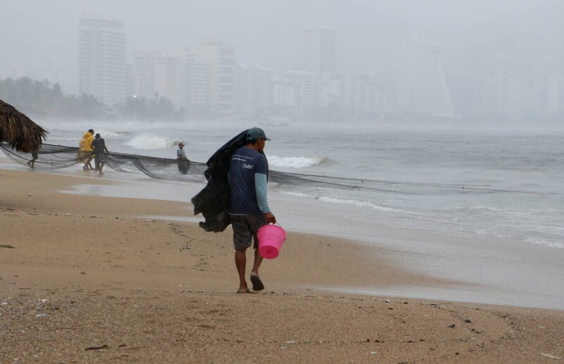 Pescadores en la playa durante la tormenta