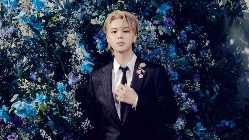 Jimin de BTS en traje azul con flores de fondo