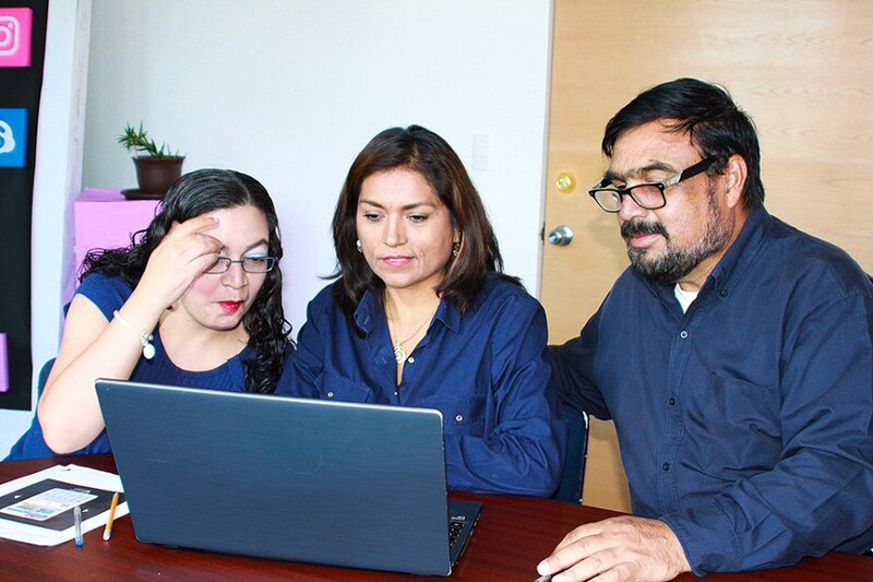 Tres personas mirando una computadora portátil