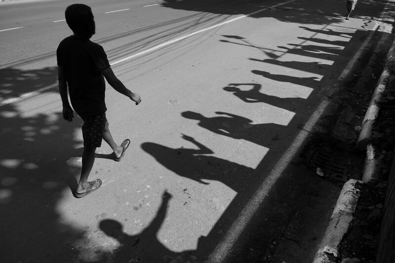 Fotografía en la que se aprecian cinco sombras y una persona caminando