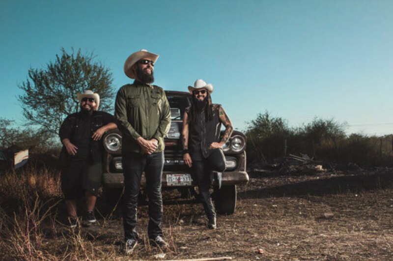Tres hombres en actitud pensativa junto a un coche antiguo