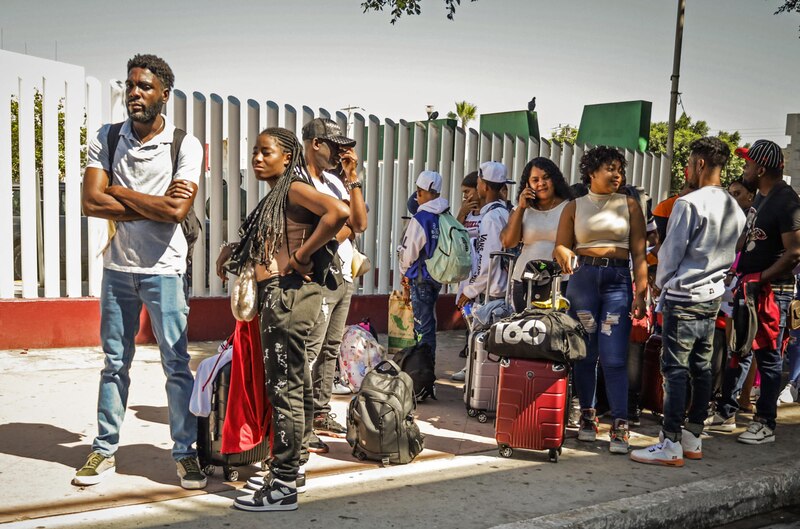 Migrantes hacen fila en una estación migratoria 'El Chaparral', este viernes en la ciudad de Tijuana en Baja California