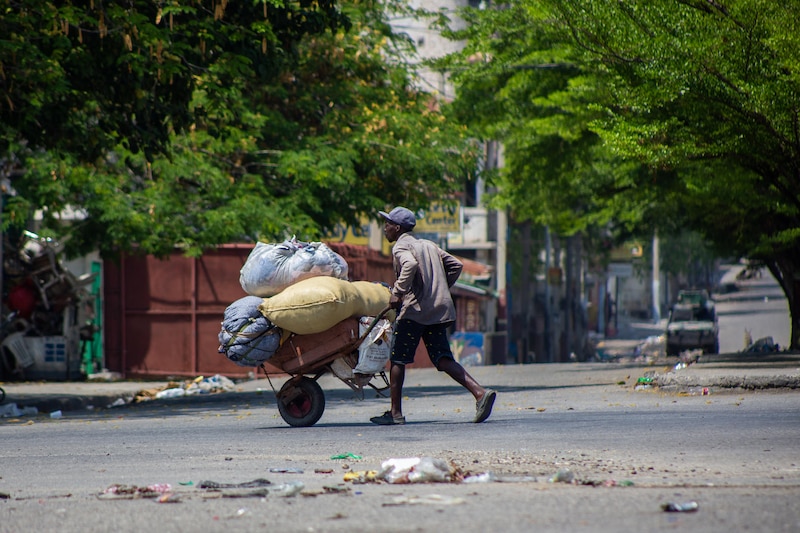 Un hombre con una carretilla en una calle llena de basura