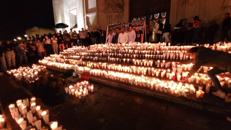 Multitud de personas encendiendo velas en la noche