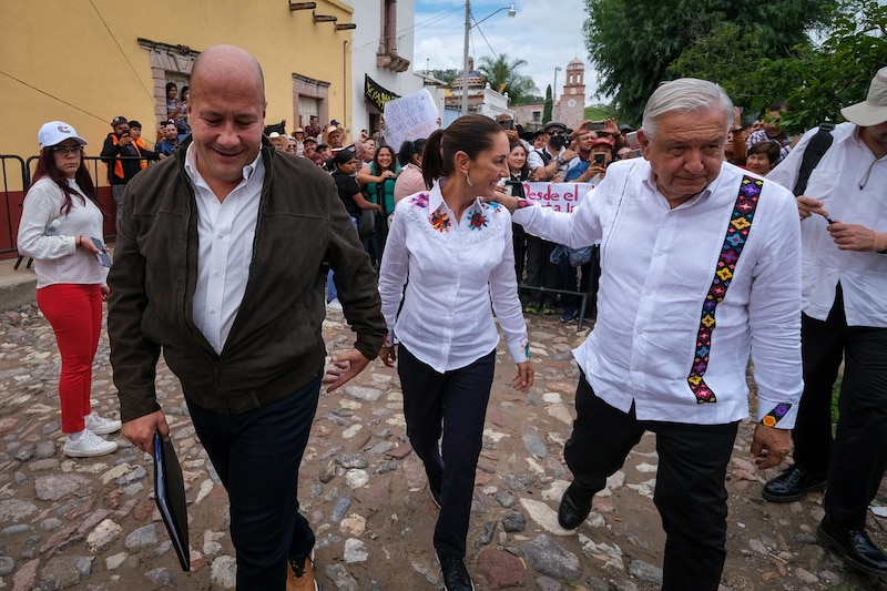 El presidente López Obrador camina junto a la doctora Beatriz Gutiérrez Müller en un evento público.