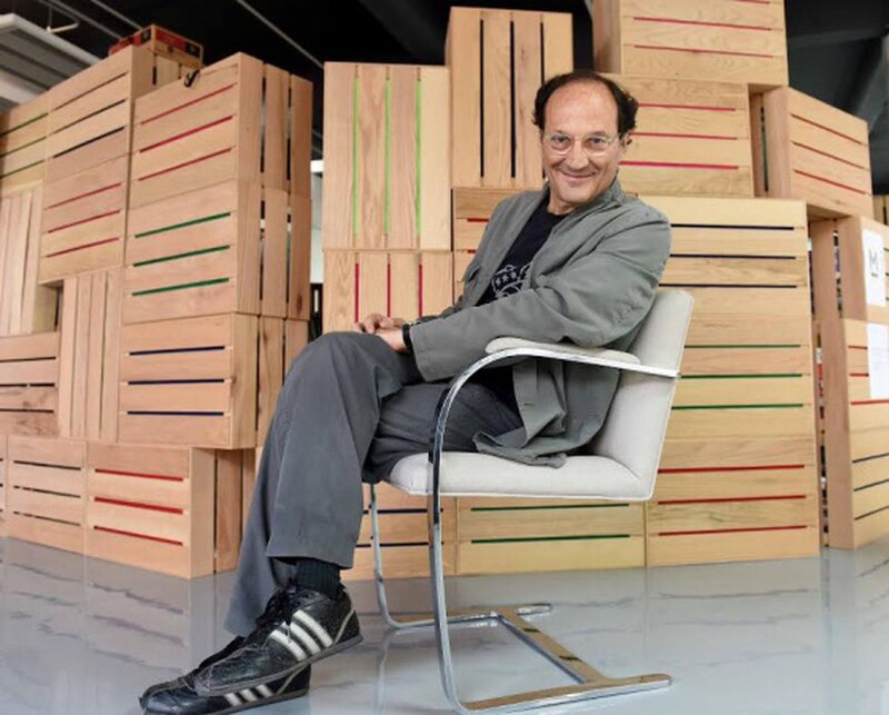 El escritor Salman Rushdie en una silla frente a un estante de libros.