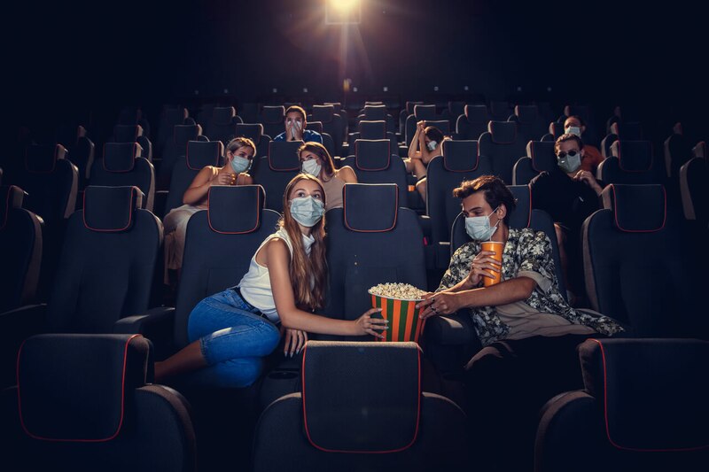 Jóvenes viendo una película en el cine con mascarillas