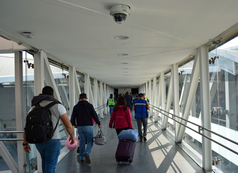 Pasajeros caminando por el pasillo entre el avión y el AICM