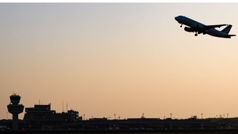 Un avión despegando de un aeropuerto al atardecer