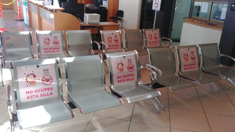 Sillas vacías en una sala de espera con carteles que dicen "No ocupes esta silla".
