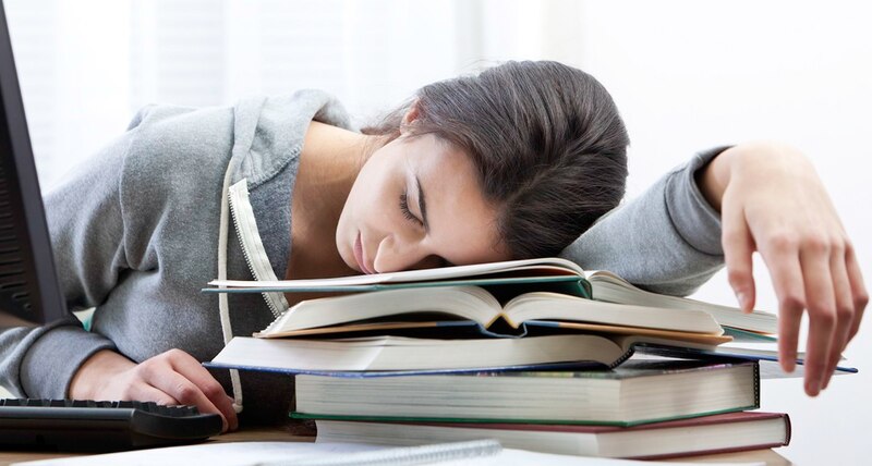 Estudiante universitaria durmiendo sobre libros