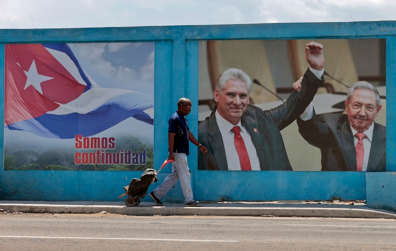 Un hombre camina frente a un mural con imágenes de Fidel Castro y Raúl Castro en La Habana, Cuba.