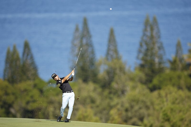 Golfista profesional realizando un swing en un campo de golf con el mar de fondo