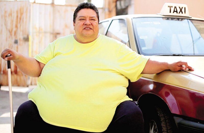 Mujer obesa junto a un taxi