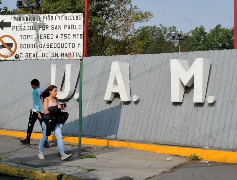 Peatones caminan frente a un letrero que dice UAM