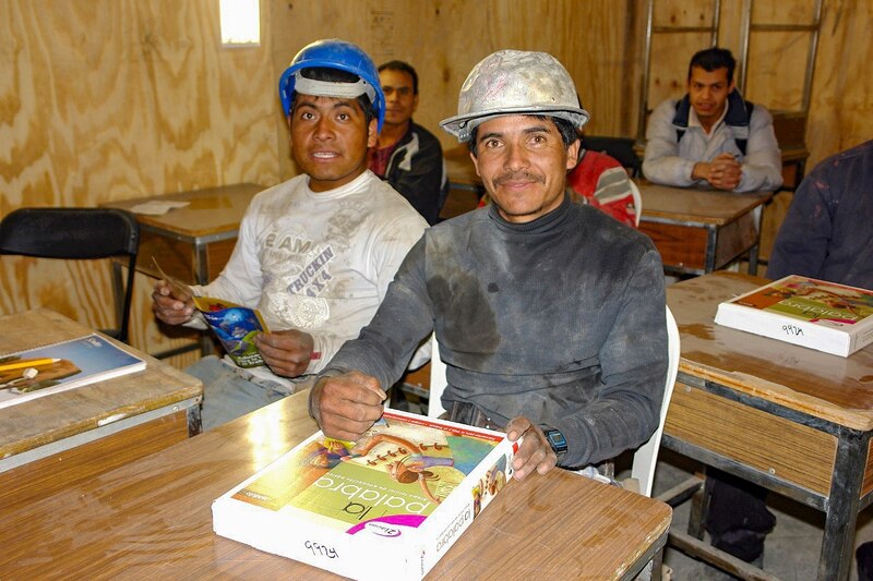 Obreros de la construcción sonríen mientras sostienen libros de texto