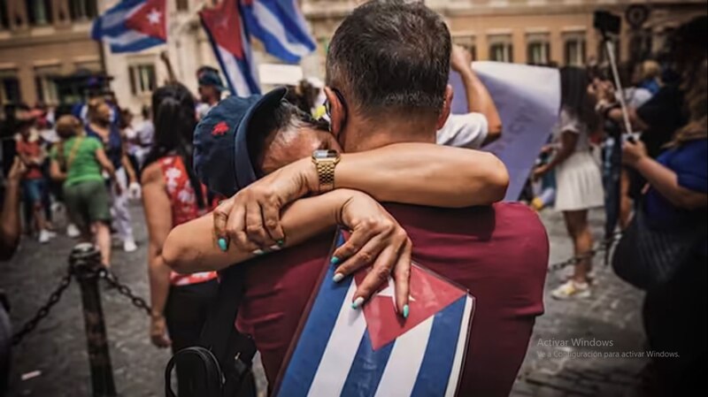 Un abrazo entre dos personas con banderas cubanas