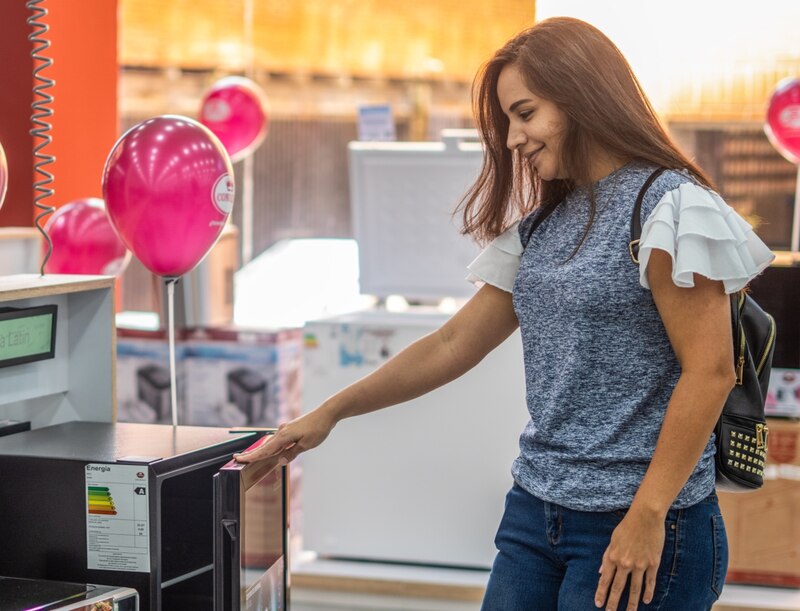 Mujer observando un refrigerador en una tienda de electrónica