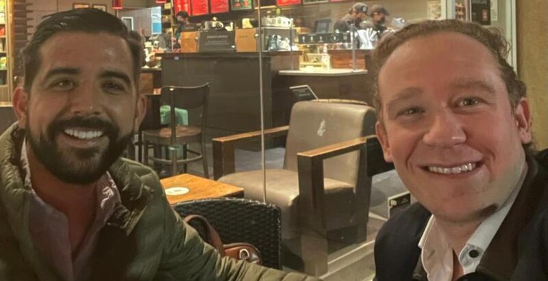 Dos hombres sonríen en una cafetería