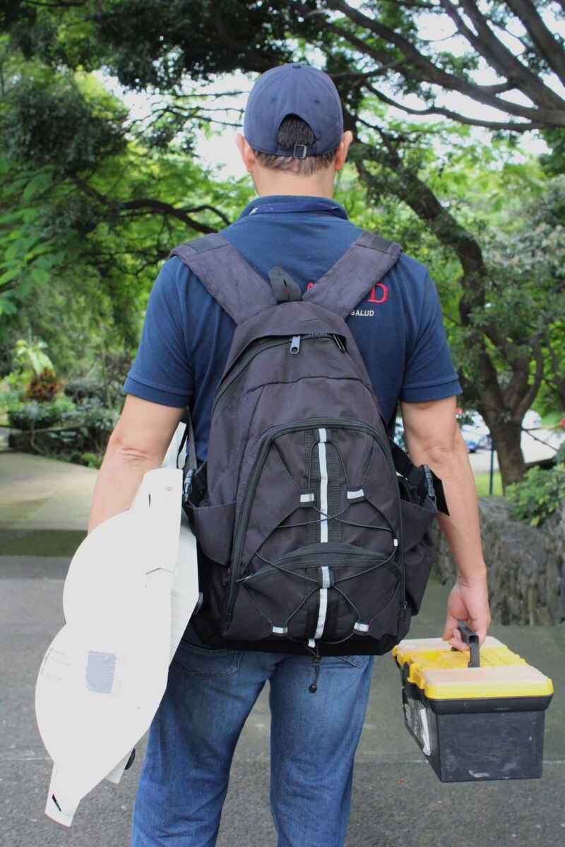 Un hombre con una mochila y una caja de herramientas