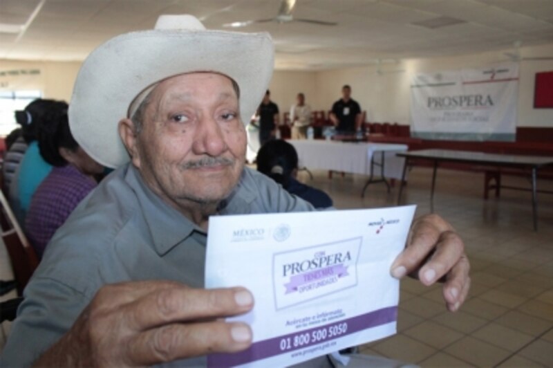 Un anciano muestra su tarjeta de PROSPERA.