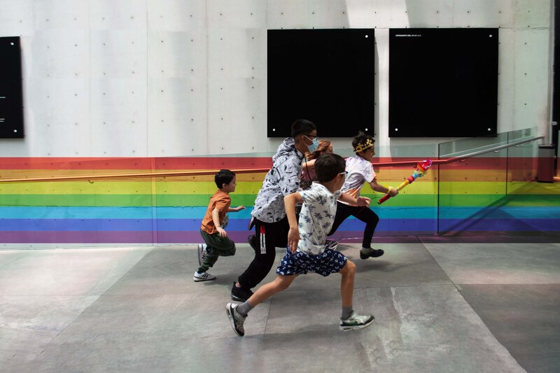 Niños corriendo en una pasarela con los colores del arco iris