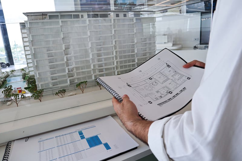 Un arquitecto sostiene los planos de un edificio en construcción.