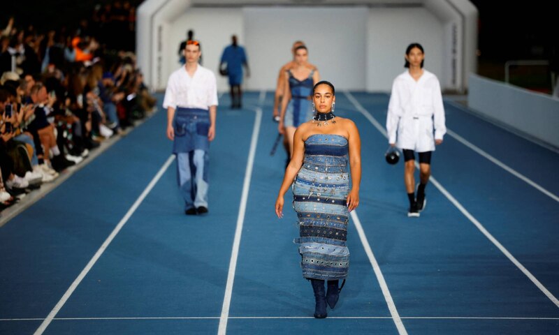 Un desfile de modas con modelos en una pasarela azul.