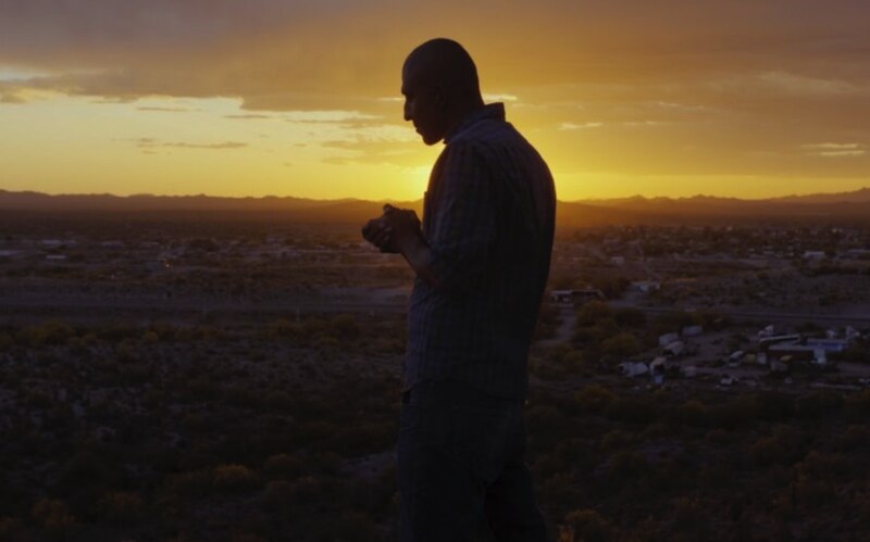 Un hombre mirando el atardecer en el desierto