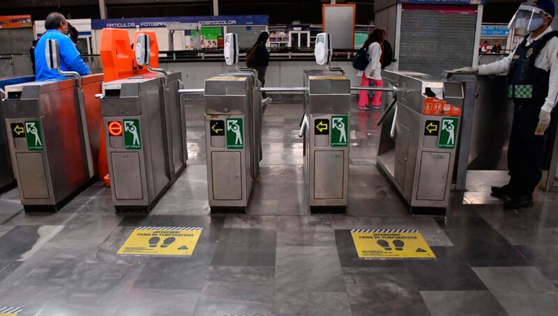 Estación de metro con torniquetes y marcas en el suelo para mantener la distancia social