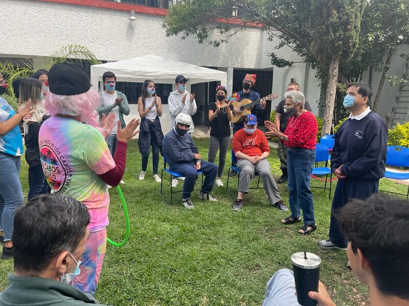 Personas mayores en un asilo de ancianos reciben una visita de payasos y músicos