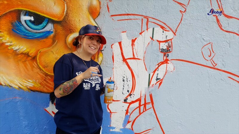 Artista urbana pinta un mural en la calle