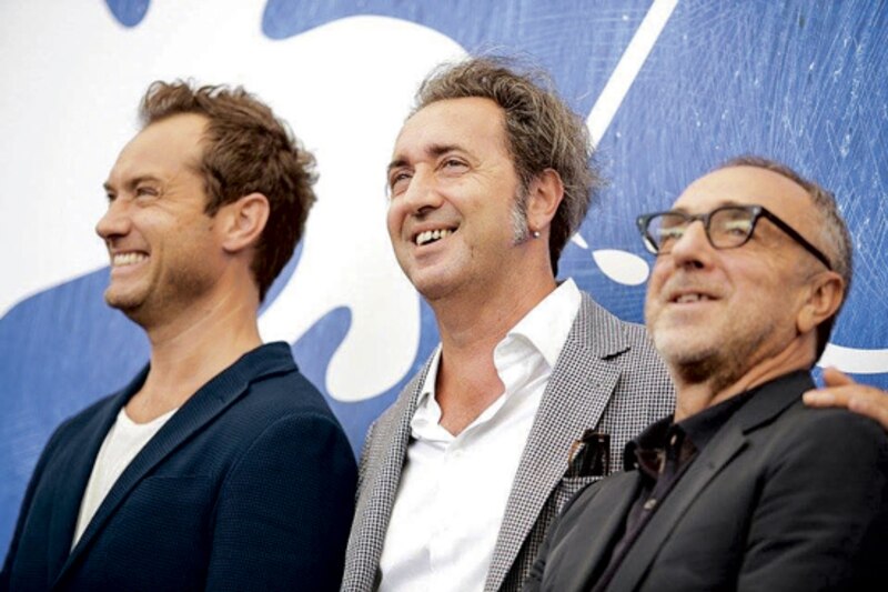 Tres hombres sonríen en una alfombra azul.