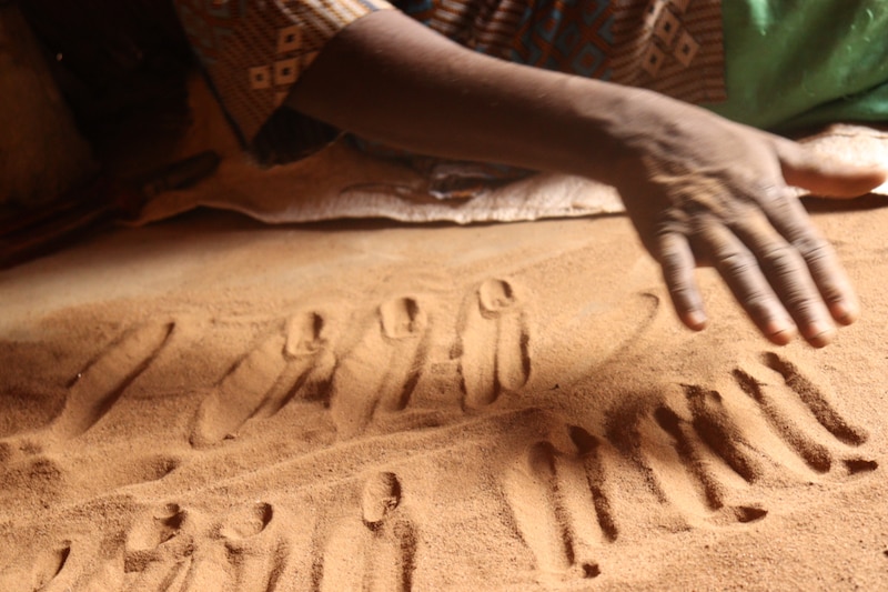 Mujer africana escribiendo en la arena