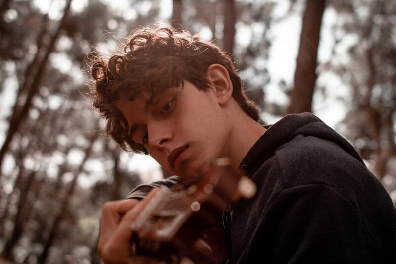 Un joven tocando la guitarra en el bosque