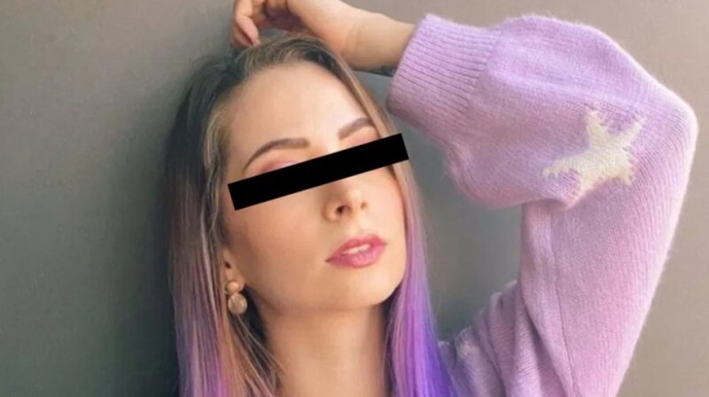 Mujer con el pelo morado y un suéter rosa