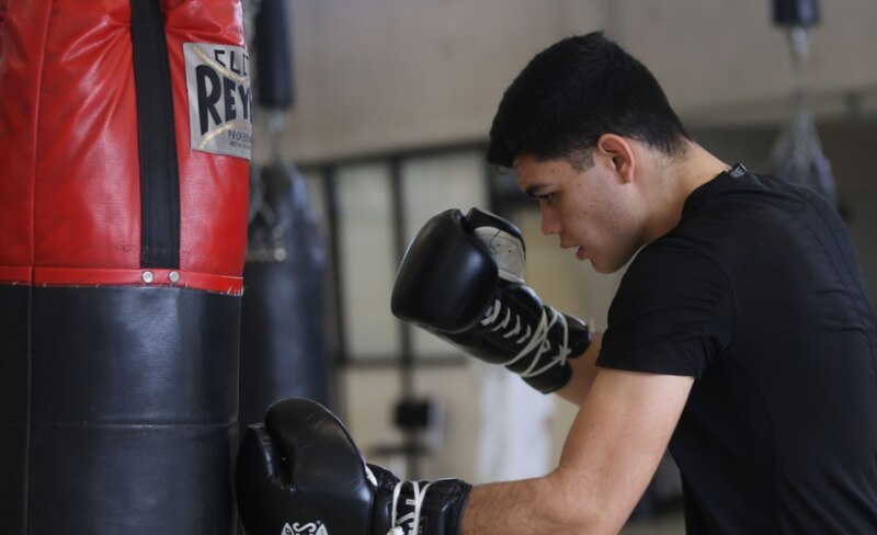 Joven boxeador entrenando con saco de boxeo