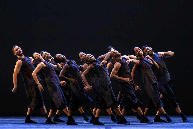 Una compañía de danza realiza una coreografía en un escenario.