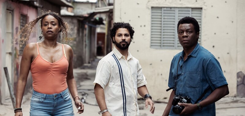 Tres personas caminando por una calle en una favela brasileña