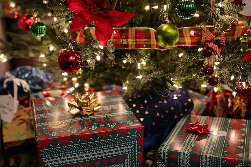 Imagen de Regalos de Navidad bajo el árbol alumbrado con luces de colores.