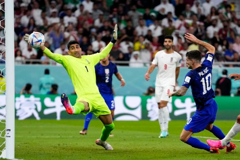 El portero de Irán, Alireza Beiranvand, despeja el balón ante la mirada del delantero estadounidense Christian Pulisic.