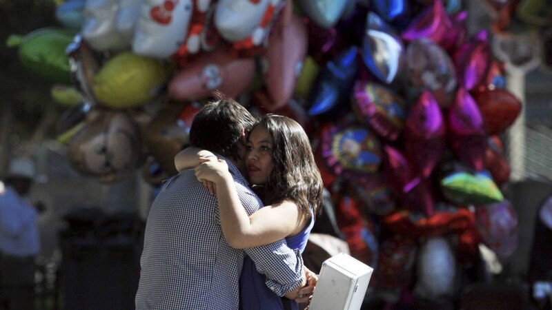 Pareja abrazándose frente a un mural de globos