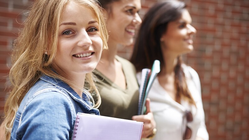 Estudiantes universitarias caminando y sonriendo
