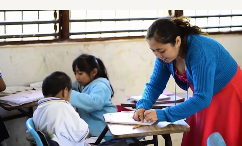 Profesora ayudando a un alumno en el aula