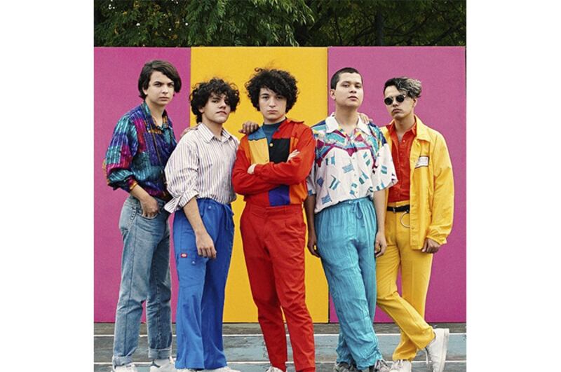 Banda de música posando frente a un fondo de colores.