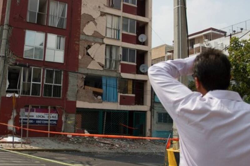 Un hombre observa un edificio dañado por un terremoto.