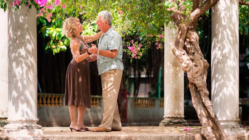 Pareja de ancianos bailando en un jardín