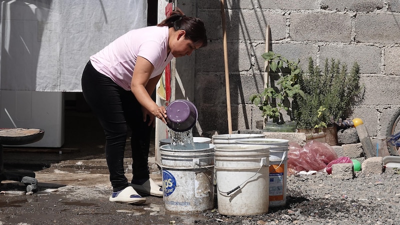 Mujer llenando cubetas de agua