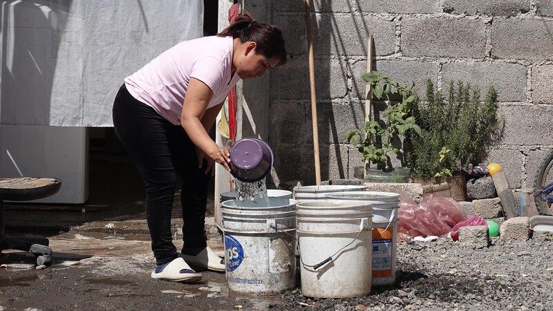 Mujer llenando cubetas de agua